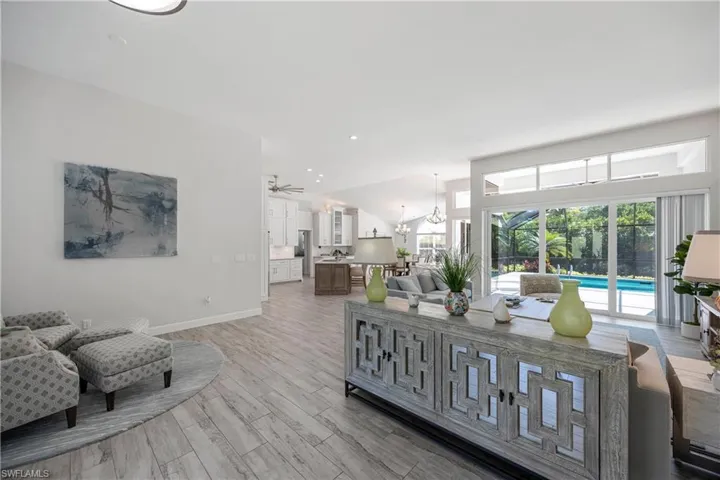 Living area featuring baseboards, ceiling fan with notable chandelier, and light wood-style flooring