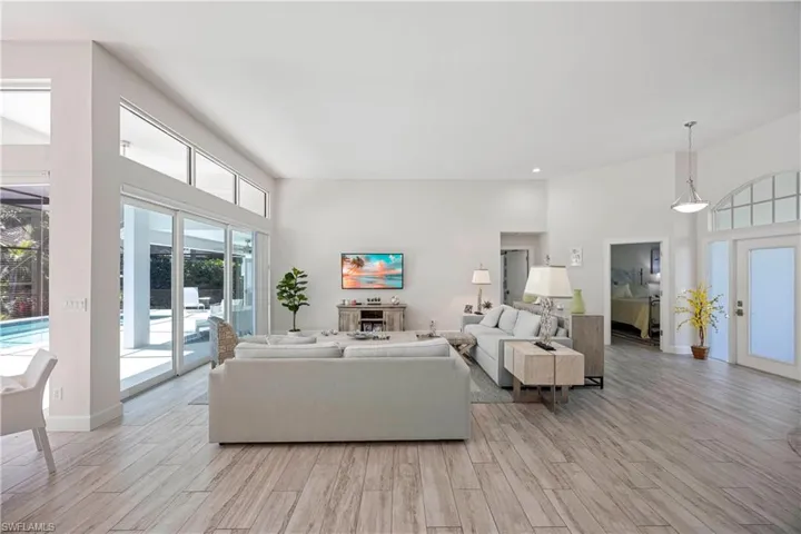 Living room with baseboards, light wood-style flooring, and a high ceiling