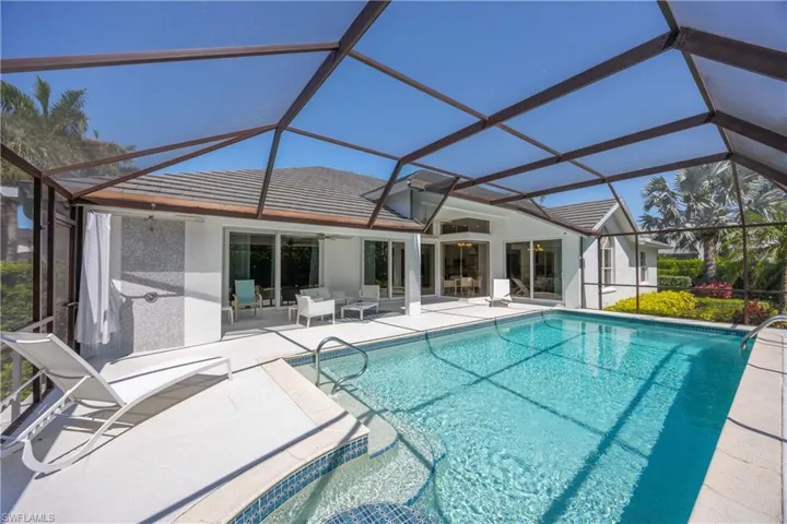 Outdoor pool featuring a ceiling fan, glass enclosure, and a patio area