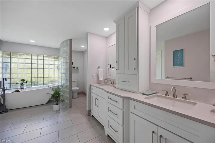 Full bath featuring toilet, double vanity, a sink, and a soaking tub