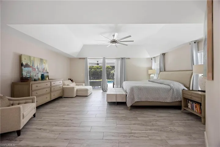 Bedroom with a ceiling fan, light wood-style flooring, and lofted ceiling