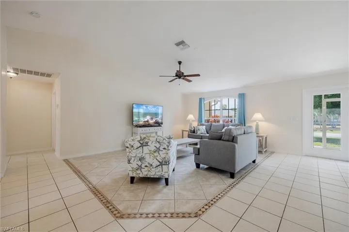 Tiled living room featuring lofted ceiling and ceiling fan