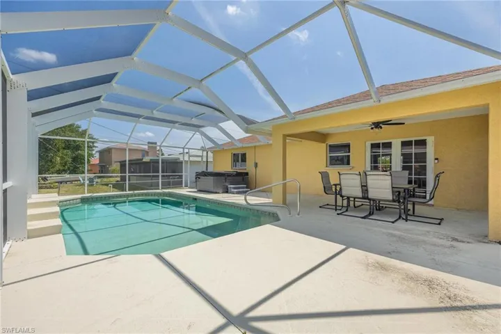 View of pool featuring ceiling fan, a lanai, a patio area, and a hot tub