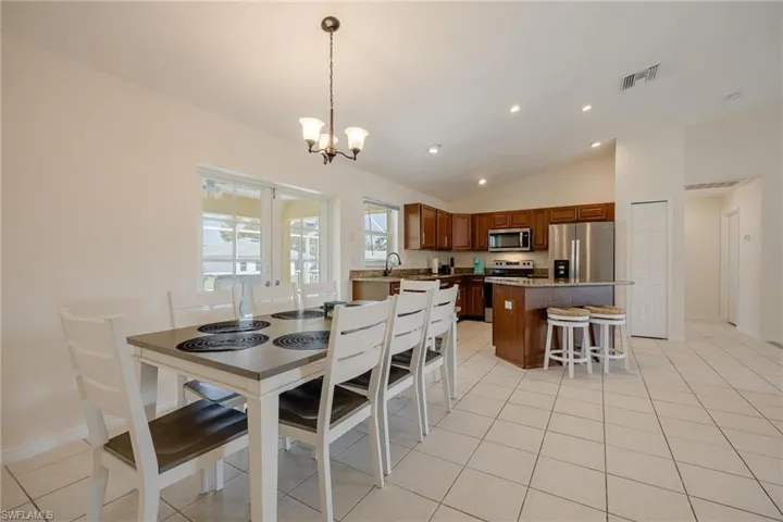 Tiled dining room featuring lofted ceiling and an inviting chandelier