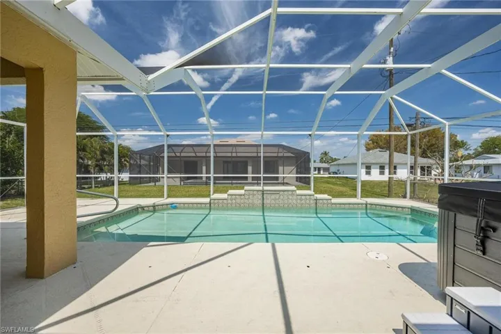 View of pool featuring glass enclosure, a yard, and a patio