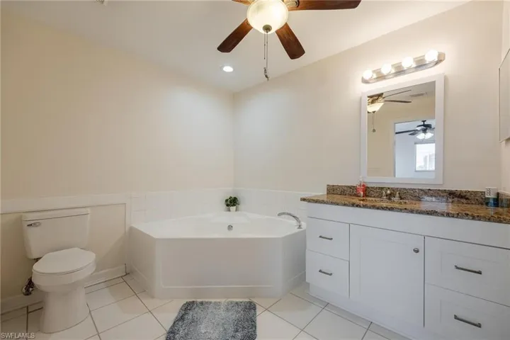 Bathroom featuring tile patterned flooring, toilet, a bathing tub, ceiling fan, and vanity