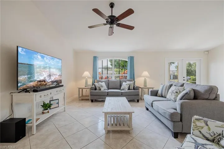 Living room featuring french doors, plenty of natural light, light tile patterned floors, and ceiling fan