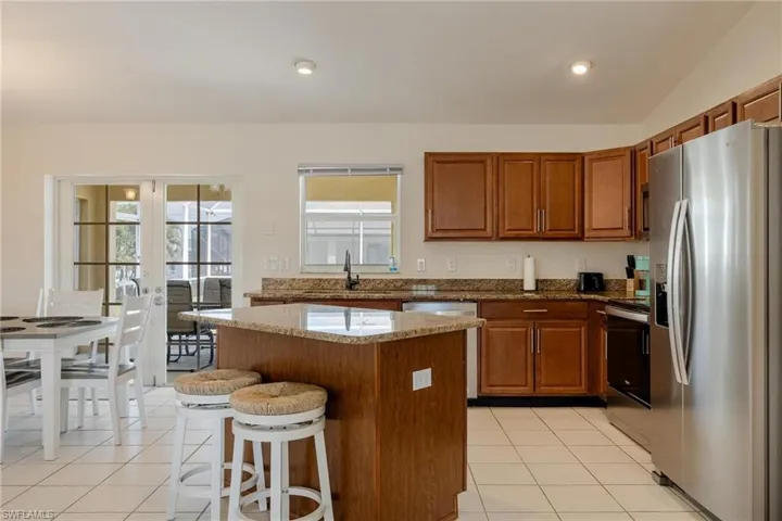Kitchen featuring light tile patterned floors, a kitchen island, sink, appliances with stainless steel finishes, and lofted ceiling
