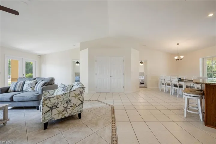 Tiled living room with vaulted ceiling and ceiling fan with notable chandelier