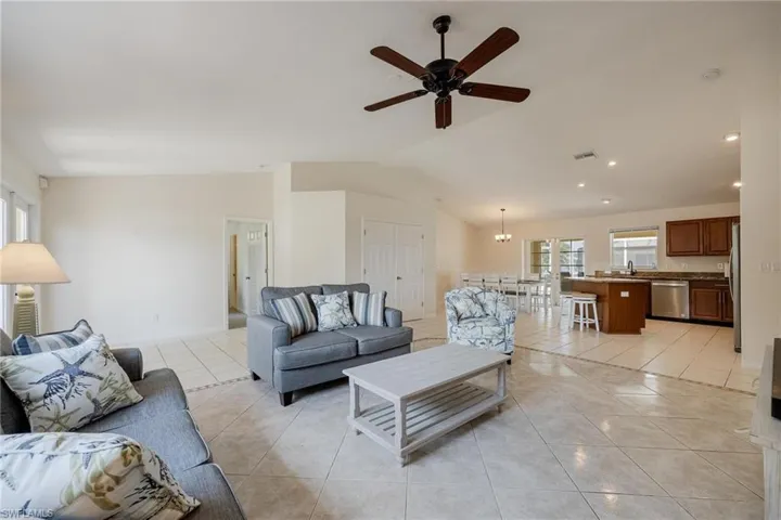 Tiled living room featuring ceiling fan, sink, and vaulted ceiling