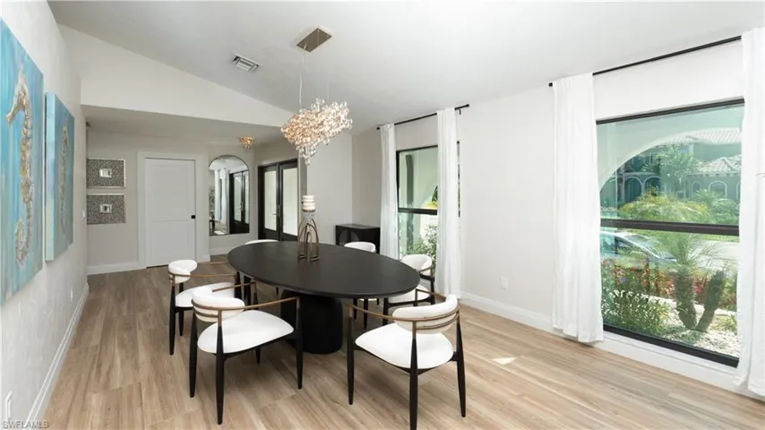 Dining space featuring light hardwood / wood-style flooring, vaulted ceiling, and an inviting chandelier