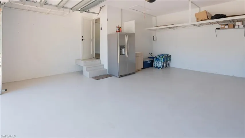 Garage featuring stainless steel refrigerator with ice dispenser and a garage door opener