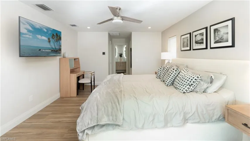 Bedroom with ceiling fan, ensuite bathroom, and light hardwood / wood-style flooring