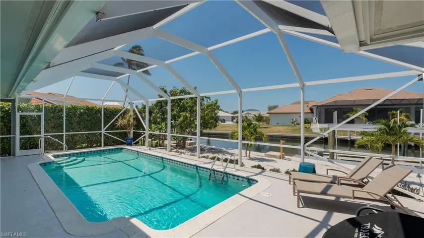 View of pool with glass enclosure and a patio area