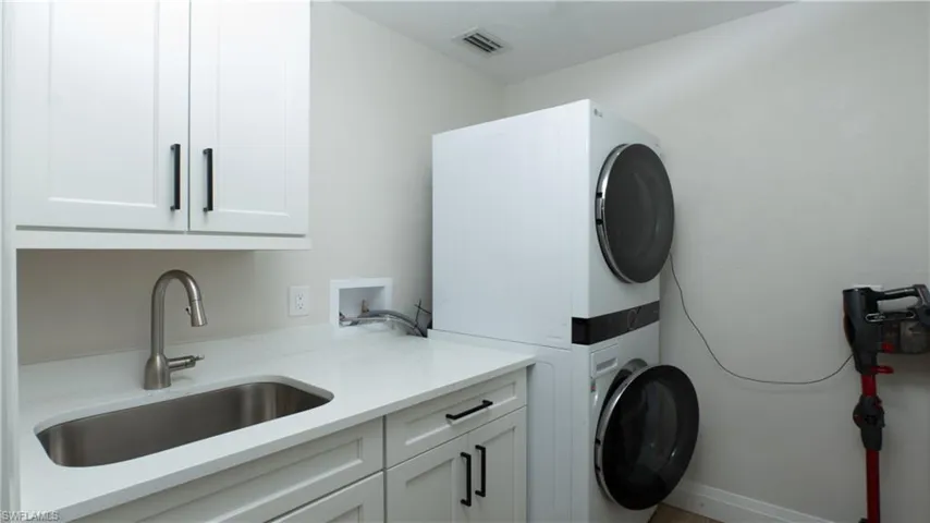 Laundry room with cabinets, sink, and stacked washer and dryer