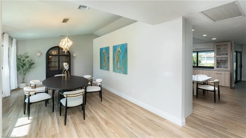 Dining area with a notable chandelier, light hardwood / wood-style floors, and vaulted ceiling