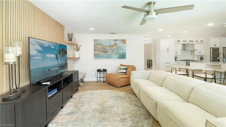 Living room with ceiling fan, light wood-type flooring, and sink