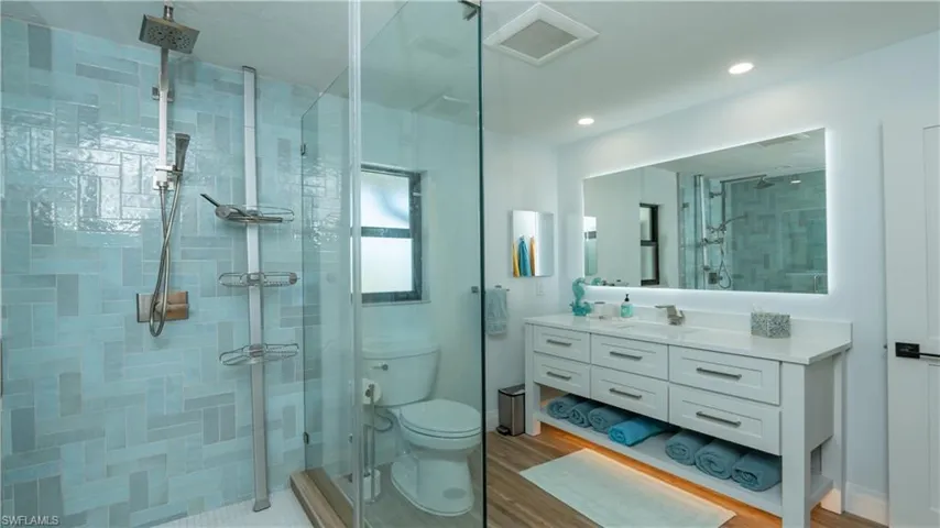 Bathroom featuring hardwood / wood-style flooring, vanity, toilet, and an enclosed shower