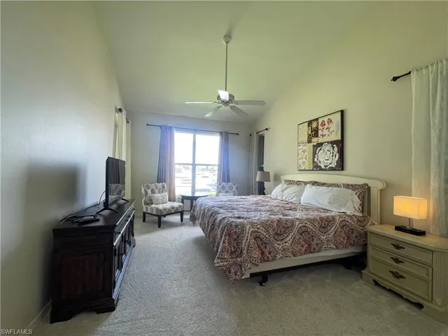 Bedroom featuring light colored carpet, lofted ceiling, and ceiling fan