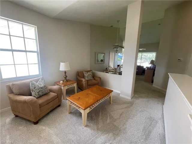 Living room with carpet flooring, a ceiling fan, and lofted ceiling