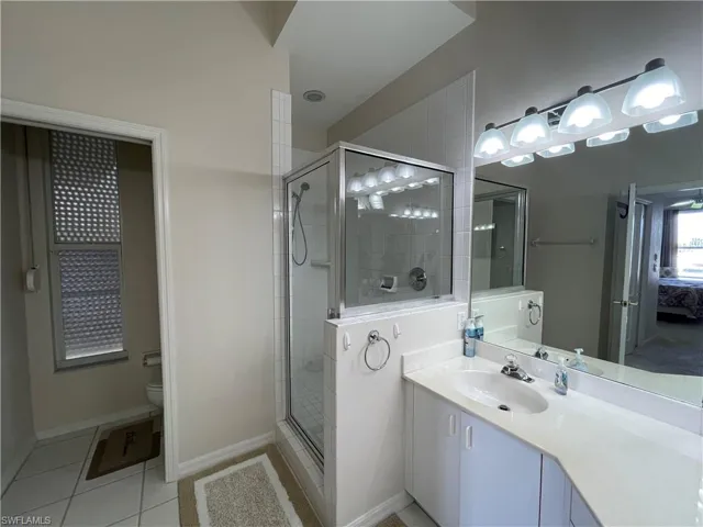 Full bath with ensuite bath, vanity, a stall shower, and light tile patterned floors