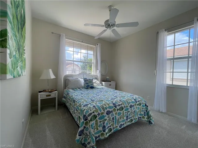 Carpeted bedroom featuring multiple windows and a ceiling fan