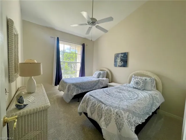 Carpeted bedroom featuring lofted ceiling and ceiling fan