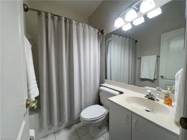Full bathroom featuring vanity, light tile patterned floors, and shower / bathtub combination with curtain