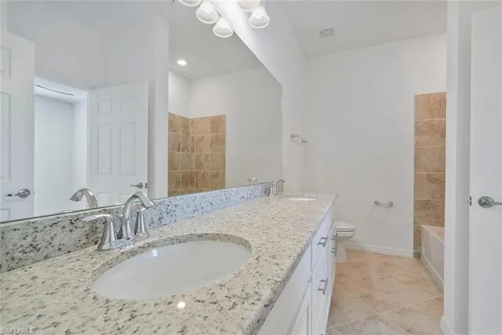 Double vanity with granite-style countertop, dual undermount sinks, and chrome faucets