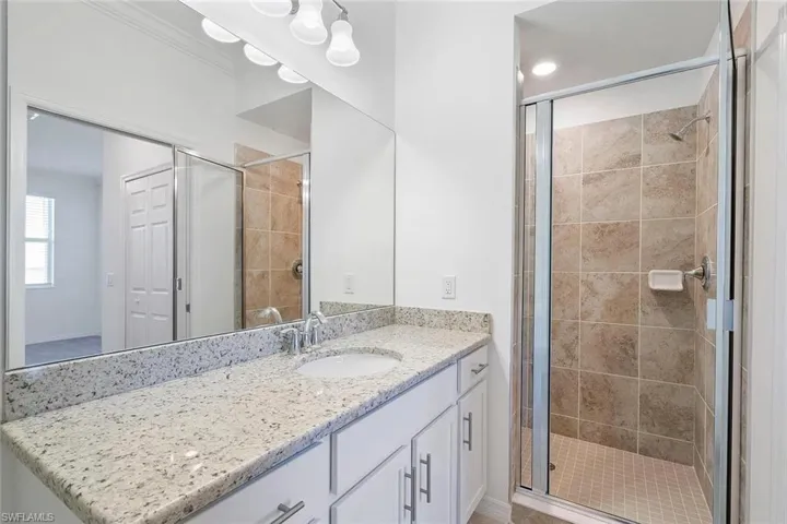 White vanity with a light speckled countertop, undermount sink, and chrome faucet