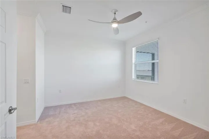 Wall-to-wall carpeting, crown molding, modern ceiling fan with lighting, and a window with blinds