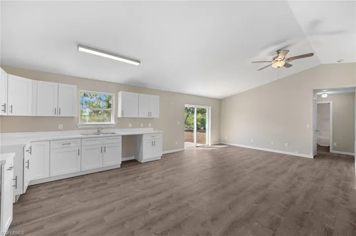 Kitchen featuring a wealth of natural light, white cabinetry, hardwood / wood-style floors, and vaulted ceiling