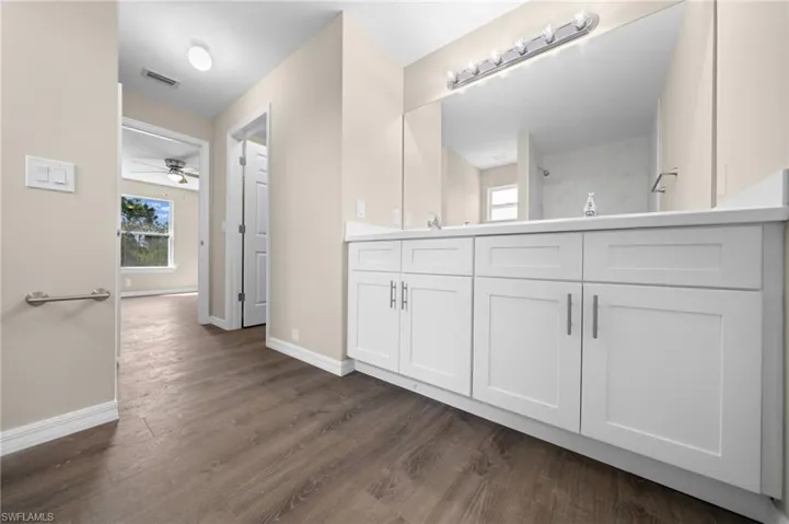 Bathroom featuring hardwood / wood-style floors, vanity, ceiling fan, and walk in shower