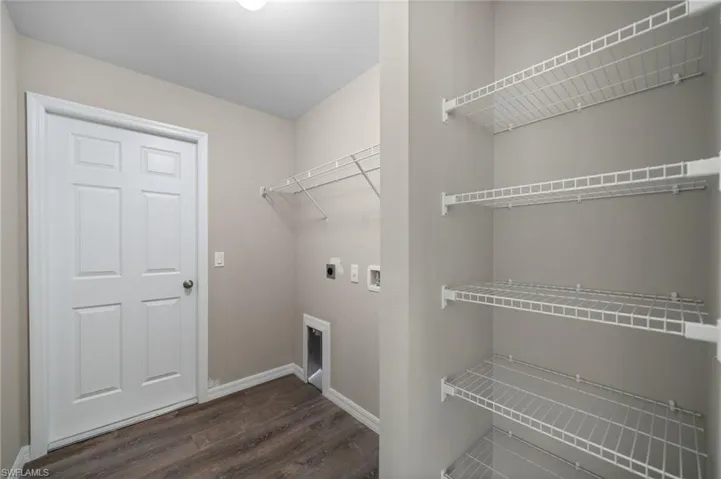 Washroom with electric dryer hookup, hookup for a washing machine, and dark hardwood / wood-style floors
