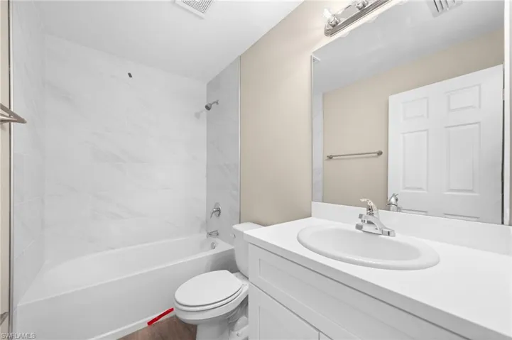 Full bathroom with vanity, toilet, wood-type flooring, and tiled shower / bath combo