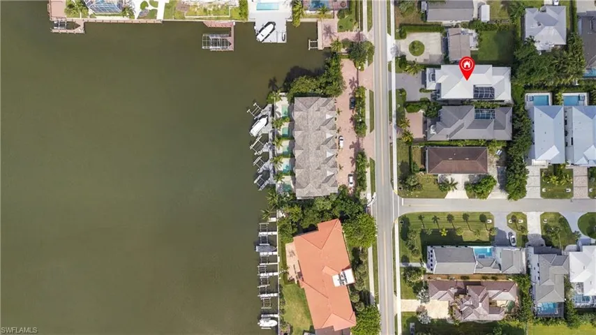 Aerial perspective of waterfront property featuring direct water access, a private boat dock, and a paved driveway