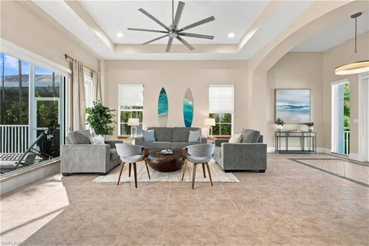 Tray ceiling with recessed lighting, large-format tile flooring, oversized windows, and modern multi-blade ceiling fan