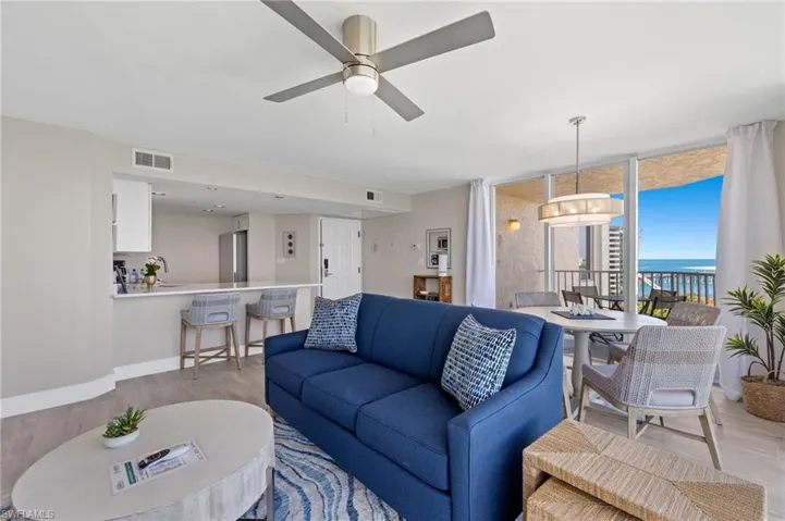 Living room with floor to ceiling windows, light hardwood / wood-style flooring, a water view, and ceiling fan with notable chandelier
