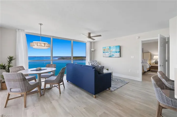 Living room featuring floor to ceiling windows, ceiling fan, a water view, and light hardwood / wood-style floors