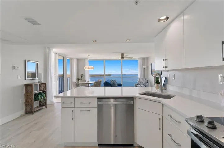Kitchen with white cabinets, a water view, hanging light fixtures, sink, and stainless steel dishwasher