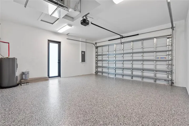 Garage with a garage door opener, electric panel, epoxy floor and electric water heater