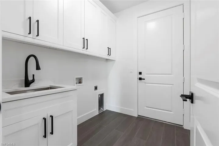 Laundry room with washer hookup, sink, dark wood-type flooring, cabinets, and electric dryer hookup