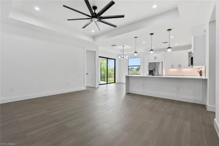 Unfurnished living room with tile flooring, ceiling fan with notable chandelier, a raised ceiling, and sink