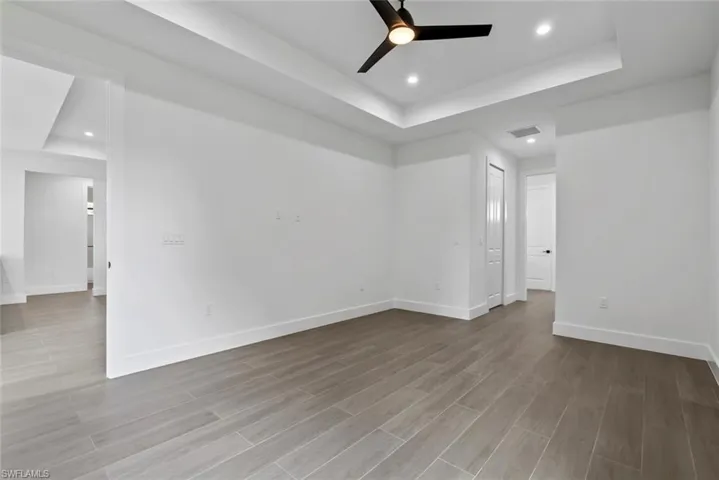 Master room with ceiling fan, a raised ceiling, and light hardwood / wood-style floors