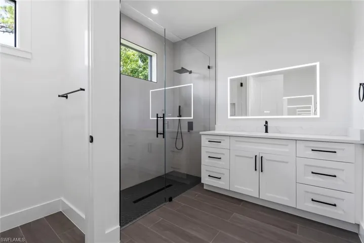 Bathroom featuring a shower with shower door, tile flooring, and vanity