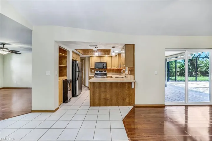 Kitchen with light tile patterned floors, a peninsula, a sink, light countertops, and appliances with stainless steel finishes