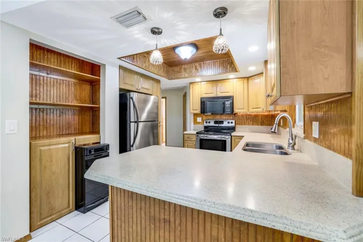 Kitchen featuring light countertops, appliances with stainless steel finishes, a peninsula, and a sink
