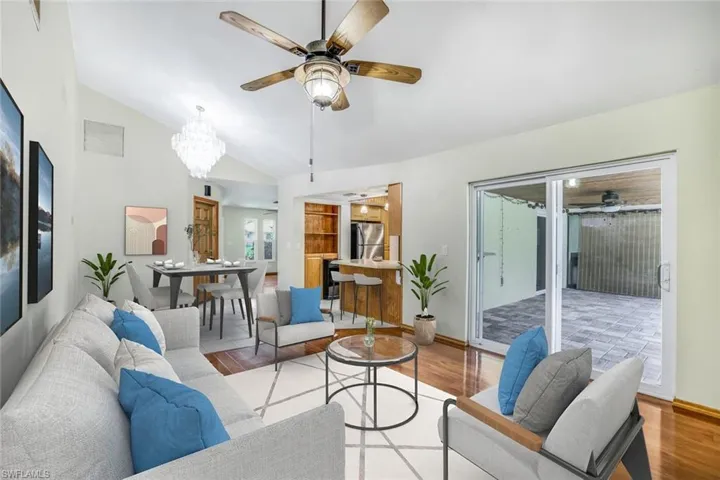 VIRTUAL STAGING Living area featuring light wood-type flooring, vaulted ceiling, and ceiling fan with notable chandelier