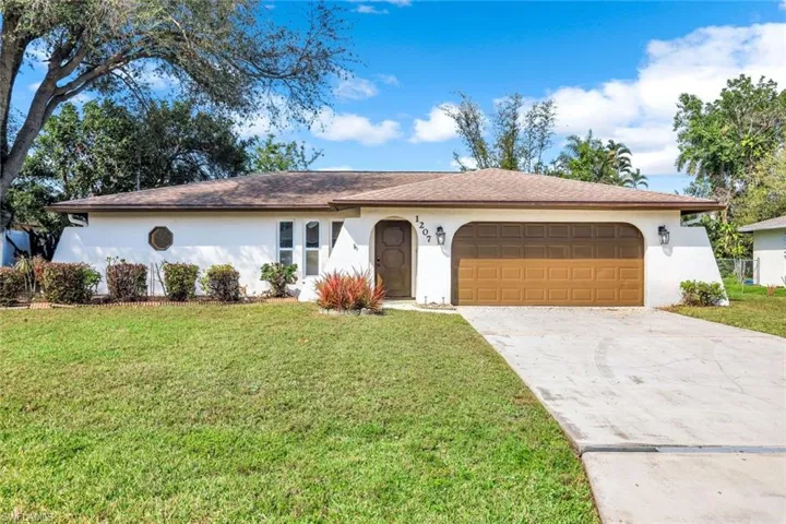 Single story home featuring a front yard, concrete driveway, and stucco siding