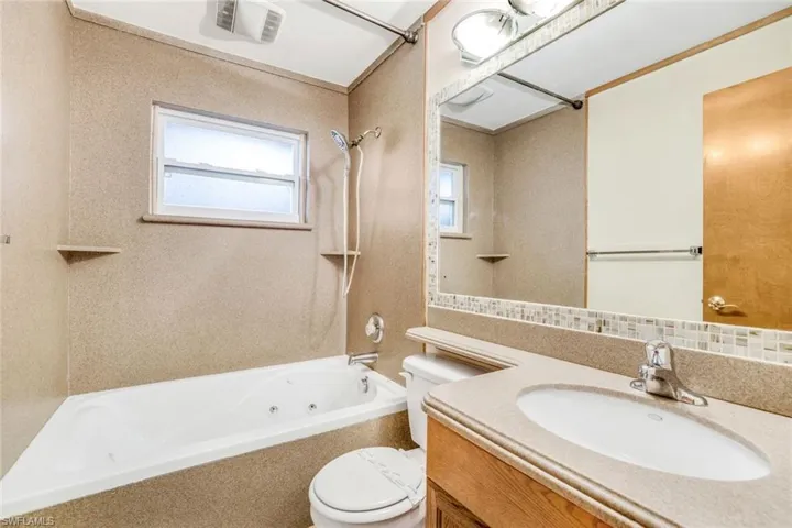 Bathroom featuring tasteful backsplash, visible vents, toilet, washtub / shower combination, and vanity